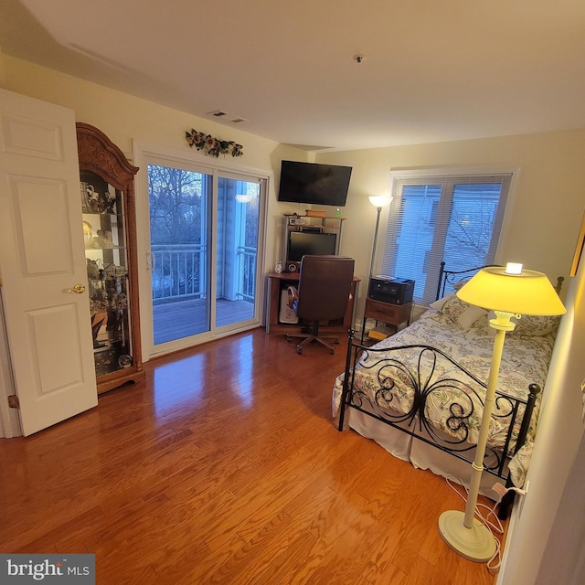 bedroom with hardwood / wood-style floors and access to exterior