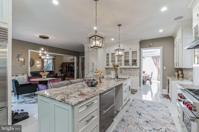 kitchen with a center island with sink, decorative backsplash, pendant lighting, and high end range