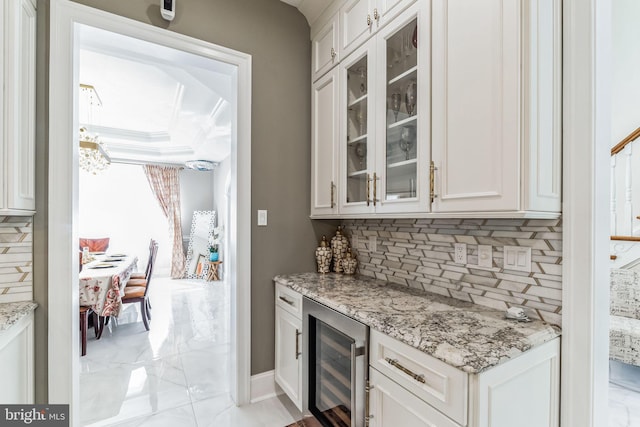 bar featuring tasteful backsplash, white cabinetry, beverage cooler, and light stone counters