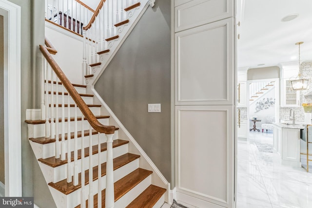 staircase featuring sink and an inviting chandelier