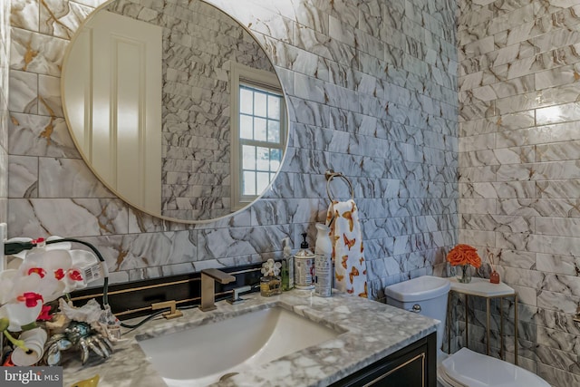 bathroom featuring vanity, toilet, and tile walls