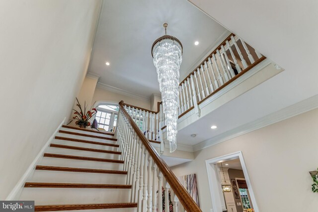 stairway with crown molding and a chandelier