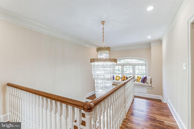 hallway with hardwood / wood-style flooring, ornamental molding, and an inviting chandelier