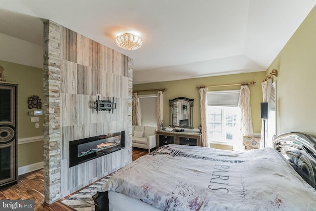 bedroom featuring a large fireplace, dark hardwood / wood-style flooring, and a tray ceiling