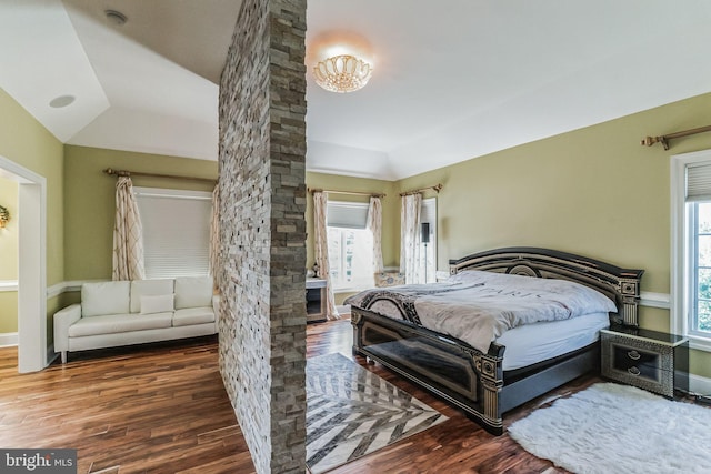 bedroom with a raised ceiling, lofted ceiling, and dark hardwood / wood-style floors