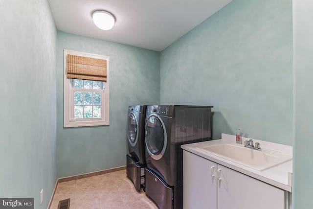 clothes washing area with washer and clothes dryer, light tile patterned flooring, cabinets, and sink