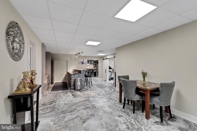 dining area featuring a barn door and a drop ceiling