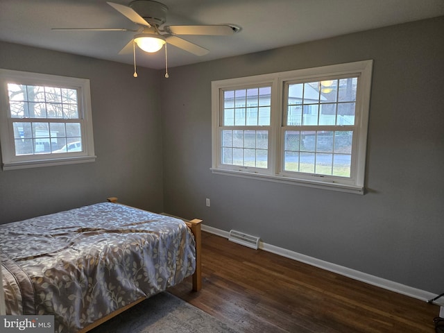 bedroom featuring ceiling fan, dark wood-type flooring, and multiple windows