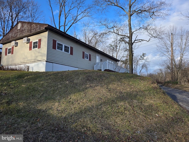 view of side of property featuring a wall mounted air conditioner and a yard