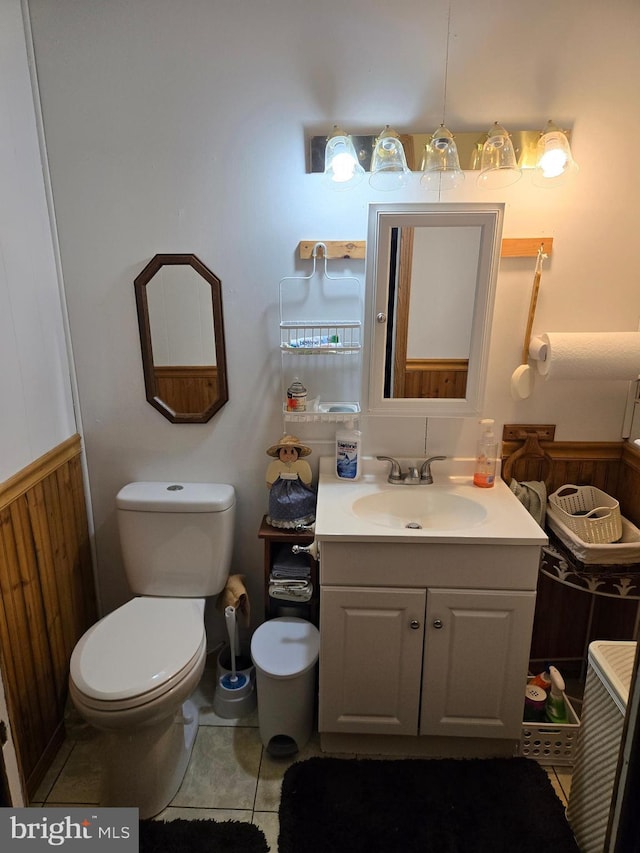 bathroom with tile patterned flooring, vanity, toilet, and wood walls