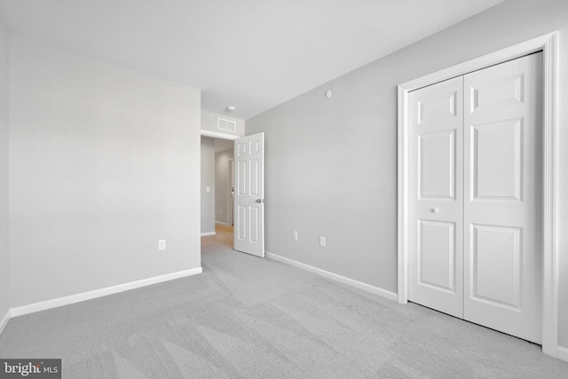 unfurnished bedroom with light colored carpet and a closet