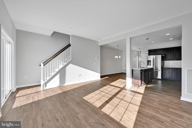 unfurnished living room featuring hardwood / wood-style flooring, a notable chandelier, and sink