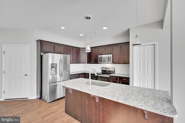 kitchen with hanging light fixtures, appliances with stainless steel finishes, tasteful backsplash, dark brown cabinets, and a breakfast bar area