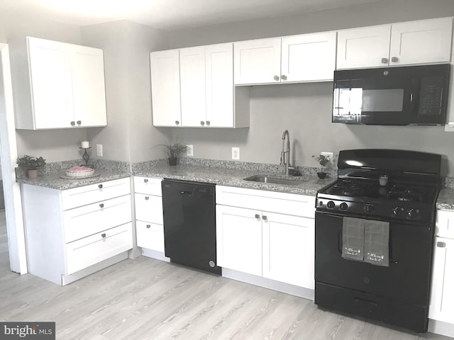 kitchen with black appliances, white cabinetry, and sink