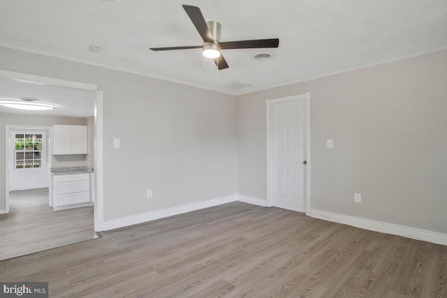 empty room featuring a textured ceiling, light hardwood / wood-style floors, ceiling fan, and ornamental molding