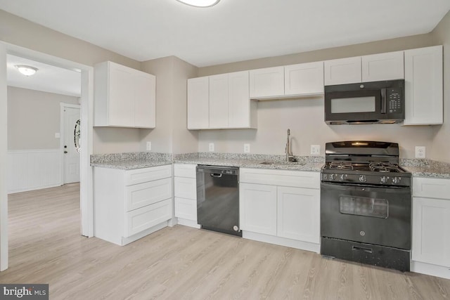 kitchen featuring light stone countertops, sink, black appliances, light hardwood / wood-style floors, and white cabinetry