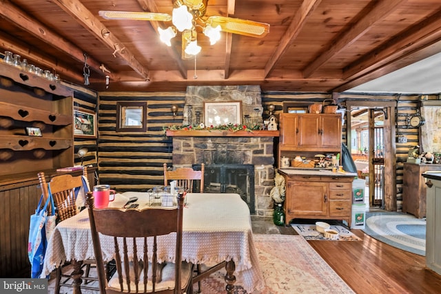 dining room with hardwood / wood-style floors, a fireplace, ceiling fan, wooden ceiling, and beam ceiling