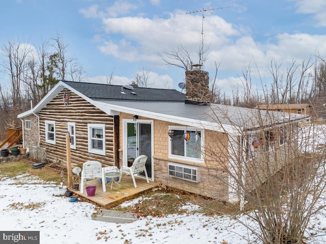 snow covered rear of property with a deck