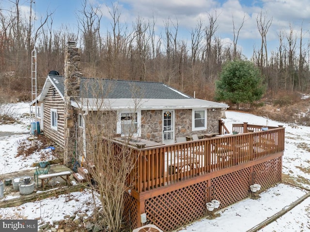 snow covered house featuring cooling unit and a wooden deck