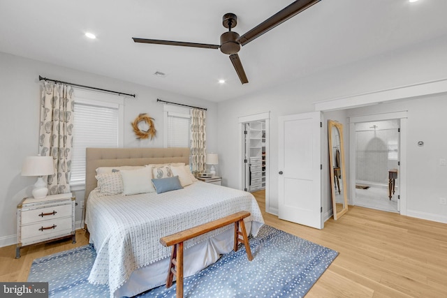 bedroom with light wood-type flooring, ceiling fan, a spacious closet, connected bathroom, and a closet