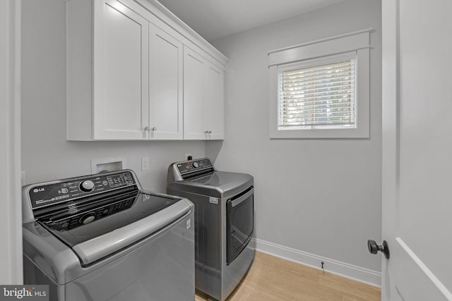 laundry area with cabinets, light hardwood / wood-style floors, and washing machine and dryer