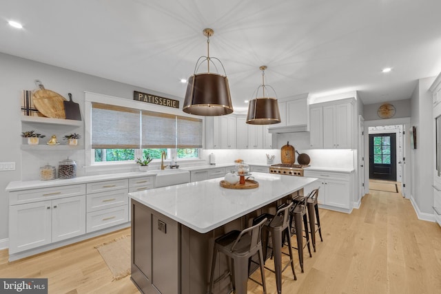 kitchen with sink, pendant lighting, white cabinets, a center island, and light hardwood / wood-style floors