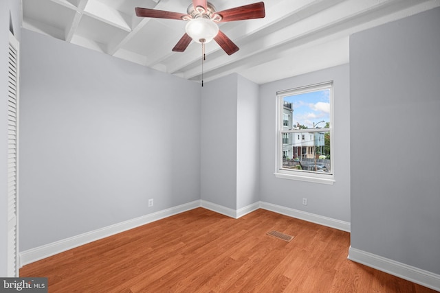 spare room with beamed ceiling, light wood-type flooring, and ceiling fan