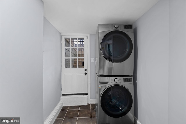 laundry area featuring stacked washing maching and dryer and dark tile patterned flooring