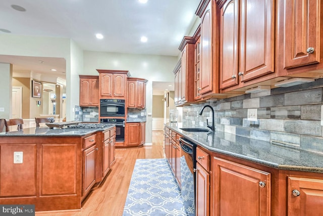 kitchen featuring a center island, black appliances, sink, decorative backsplash, and light wood-type flooring