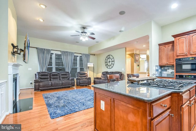 kitchen with ceiling fan, tasteful backsplash, light hardwood / wood-style flooring, oven, and stainless steel gas stovetop