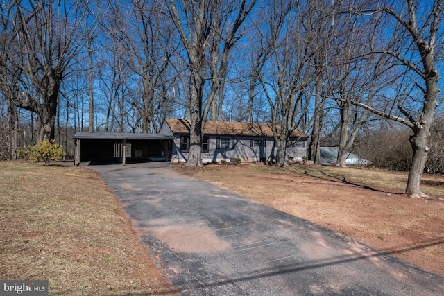 view of front of home with aphalt driveway, an attached carport, and a front yard