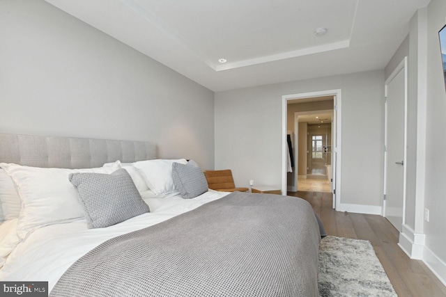 bedroom with wood-type flooring and a tray ceiling