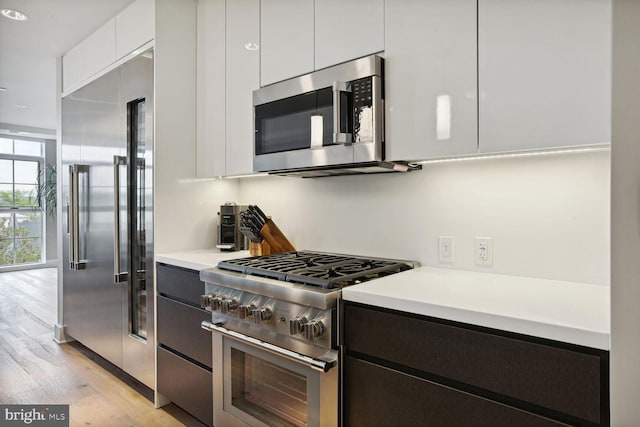 kitchen featuring high quality appliances, white cabinetry, and light hardwood / wood-style flooring