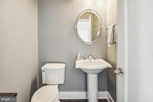 bathroom featuring toilet, baseboards, and a sink