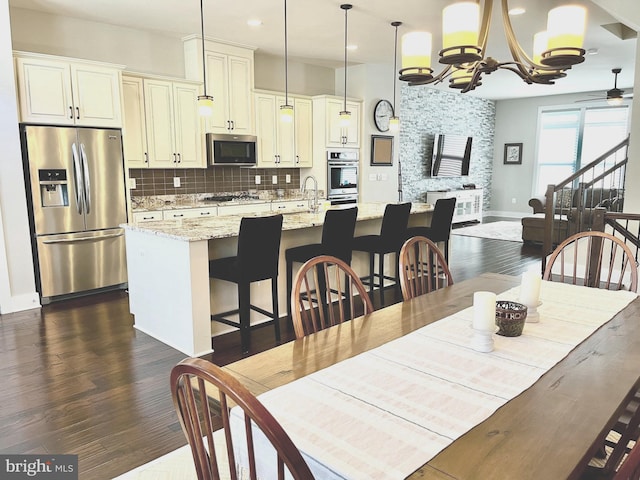 dining room featuring dark wood finished floors, ceiling fan with notable chandelier, and baseboards