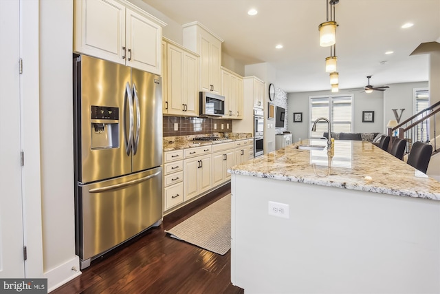 kitchen with an island with sink, a sink, tasteful backsplash, dark wood-style floors, and stainless steel appliances