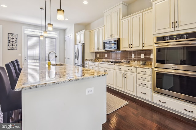 kitchen featuring sink, an island with sink, hanging light fixtures, and appliances with stainless steel finishes