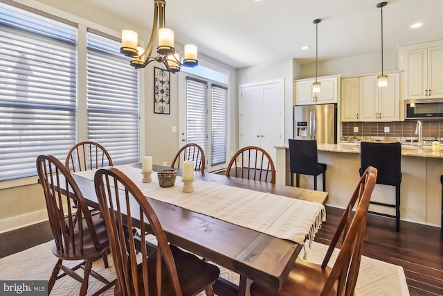 dining space with a chandelier, dark wood-type flooring, and sink