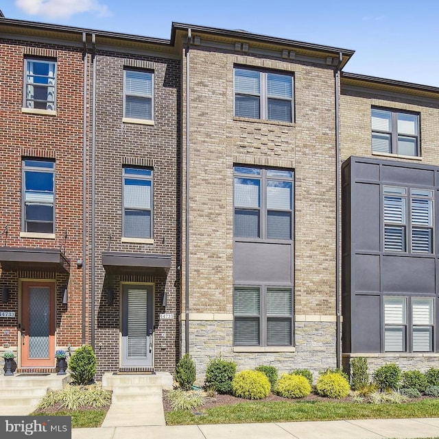 townhome / multi-family property featuring brick siding and stone siding