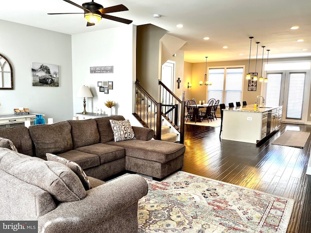 living area featuring ceiling fan with notable chandelier, stairway, recessed lighting, and dark wood-style flooring