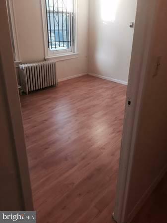 unfurnished room with wood-type flooring and radiator