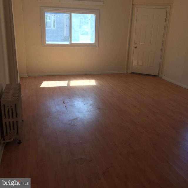 unfurnished room with hardwood / wood-style floors and radiator heating unit