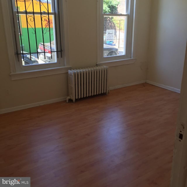 unfurnished room featuring wood-type flooring and radiator