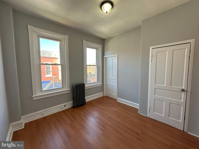 unfurnished bedroom featuring wood-type flooring, radiator heating unit, and a closet