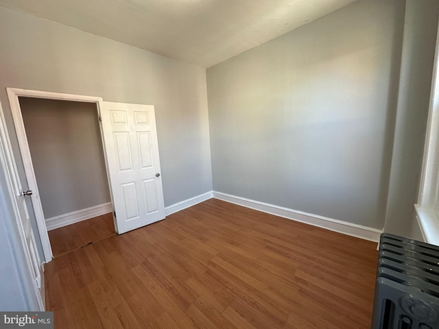 spare room with radiator heating unit, lofted ceiling, and dark wood-type flooring