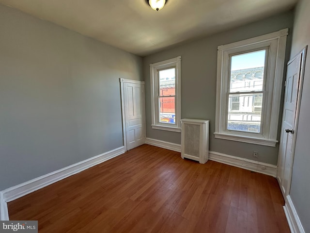 empty room featuring wood-type flooring and radiator heating unit