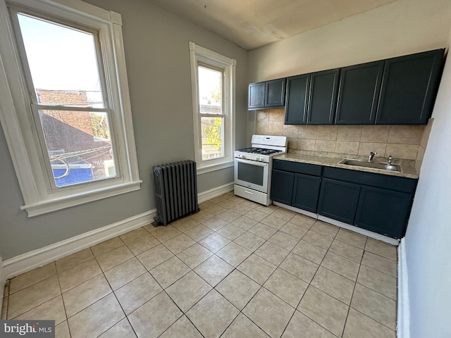 kitchen with sink, radiator heating unit, tasteful backsplash, light tile patterned floors, and white gas range oven