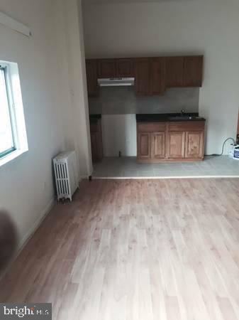 unfurnished living room featuring light hardwood / wood-style floors, sink, and radiator