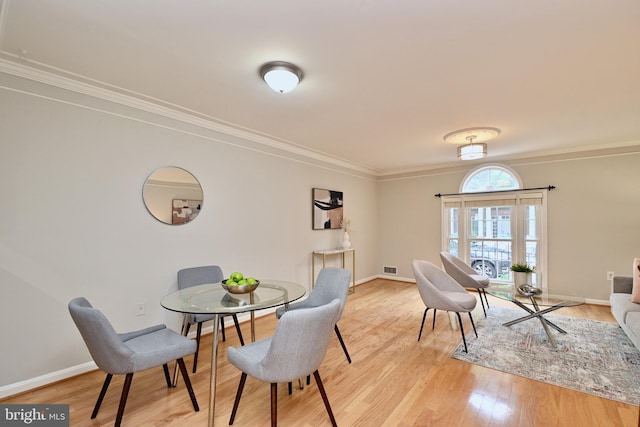 dining room with light hardwood / wood-style flooring and ornamental molding