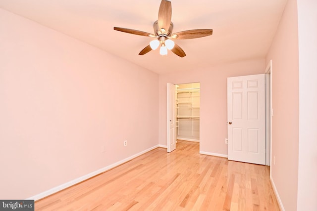 unfurnished bedroom with a walk in closet, light hardwood / wood-style flooring, a closet, and ceiling fan